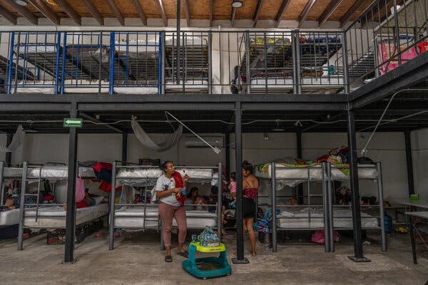 A few people lay on mattresses and two  women, one holding a baby, chatted in a cavernous migrant shelter in Ciudad Juárez, Mexico. 